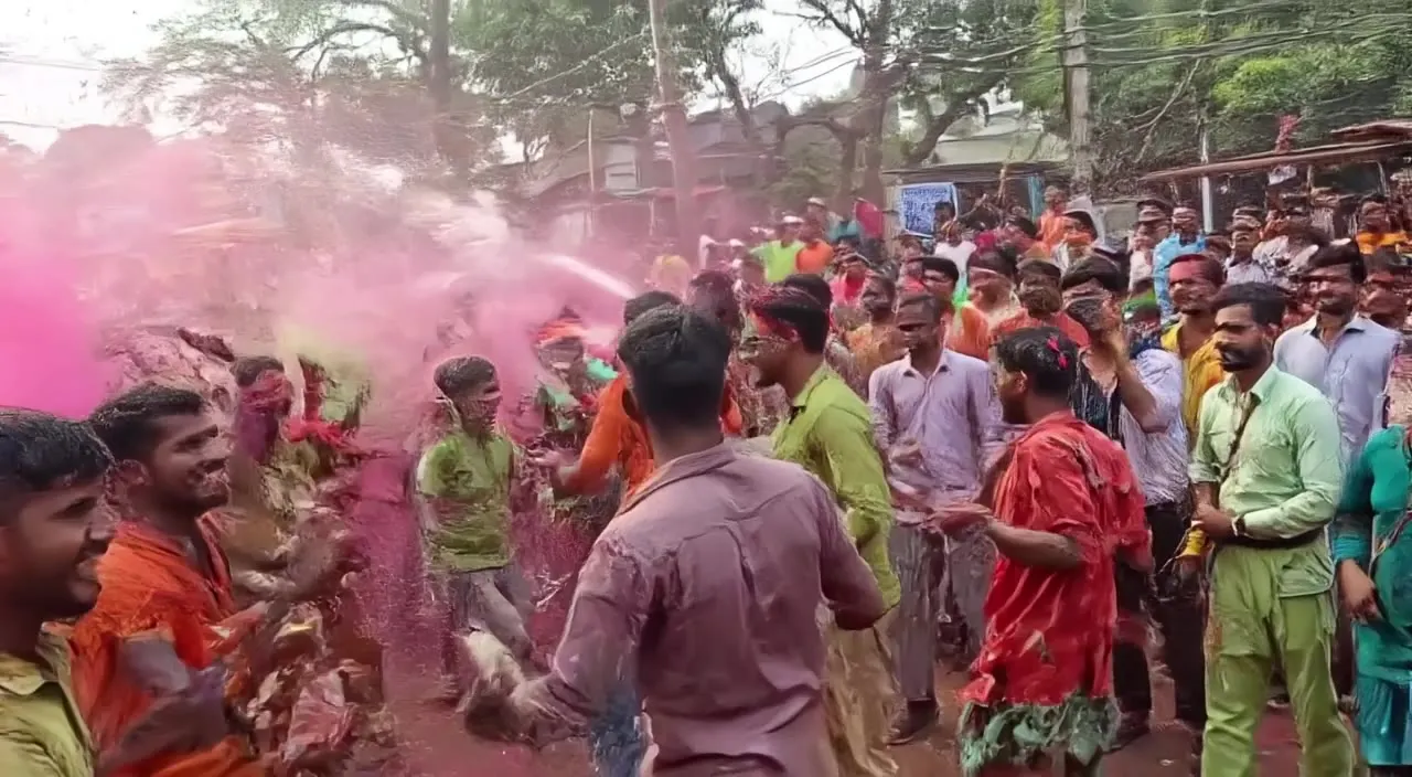 Holi in a Kolkata lane: colour, a water jet, a crowd dancing to drums.