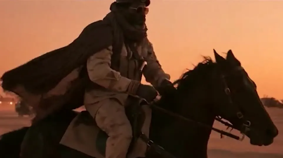 A rider on horseback crossing a desert at sunset